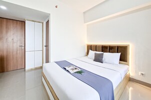 Une chambre d’hôtel avec un lit, une armoire en bois et une porte blanche.
