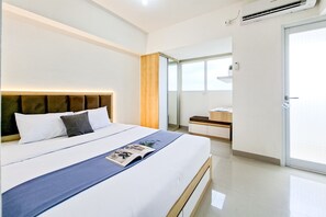 A modern hotel room with a large bed, a bedside table, a mirror, and a sliding door to the balcony. - Good Location Studio At Cisauk Point Apartment (Cisauk)