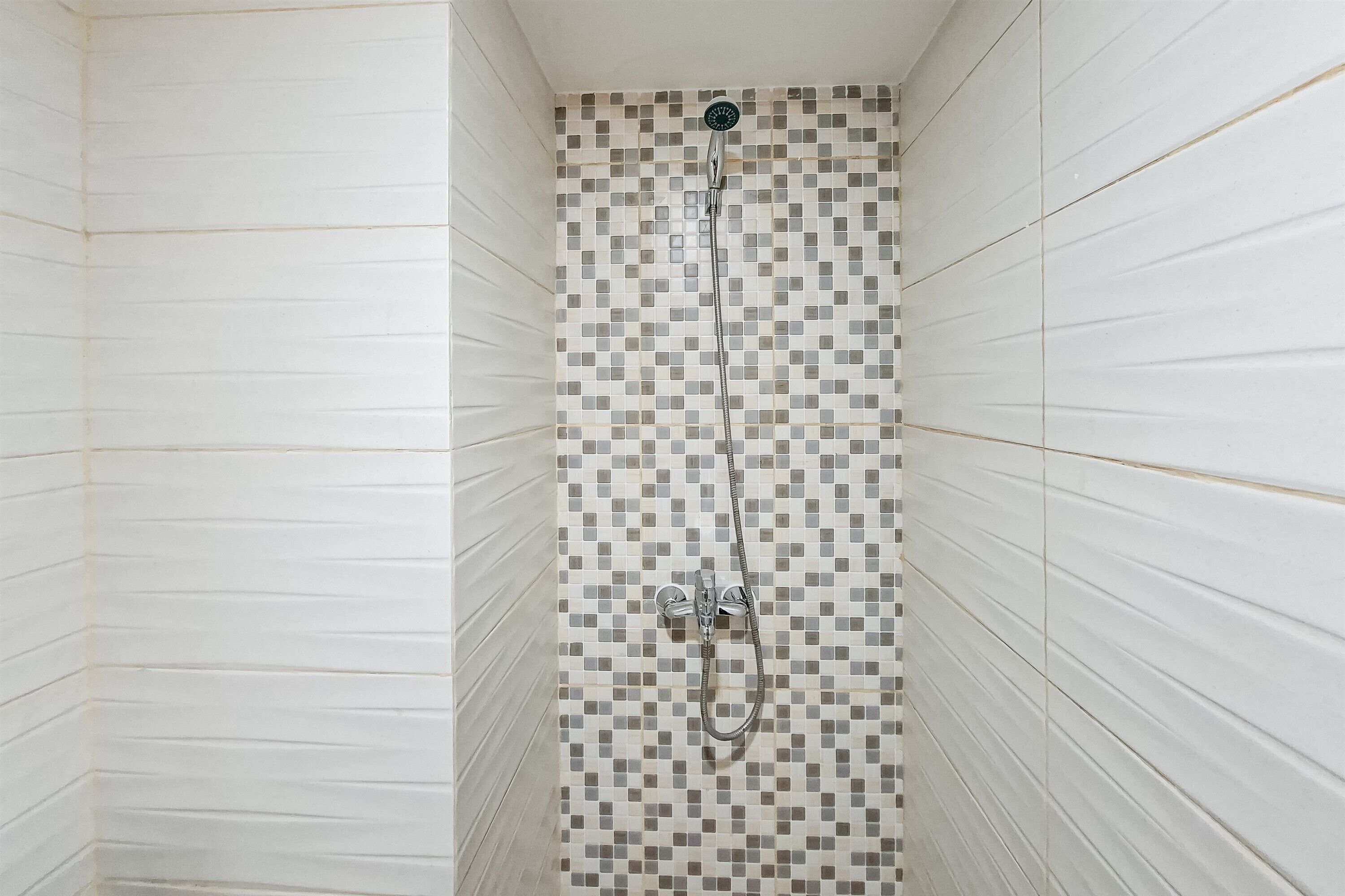 A shower with a checkered tile wall and a horizontal panel design on the sides.