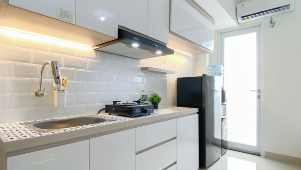 Een moderne keuken met witte kasten, een roestvrijstalen koelkast, een inbouwfornuis en een waterdispenser.