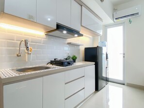 Eine moderne Küche mit weißen Schränken, einem Edelstahl-Kühlschrank, einem eingebauten Herd und einem Wasserspender.