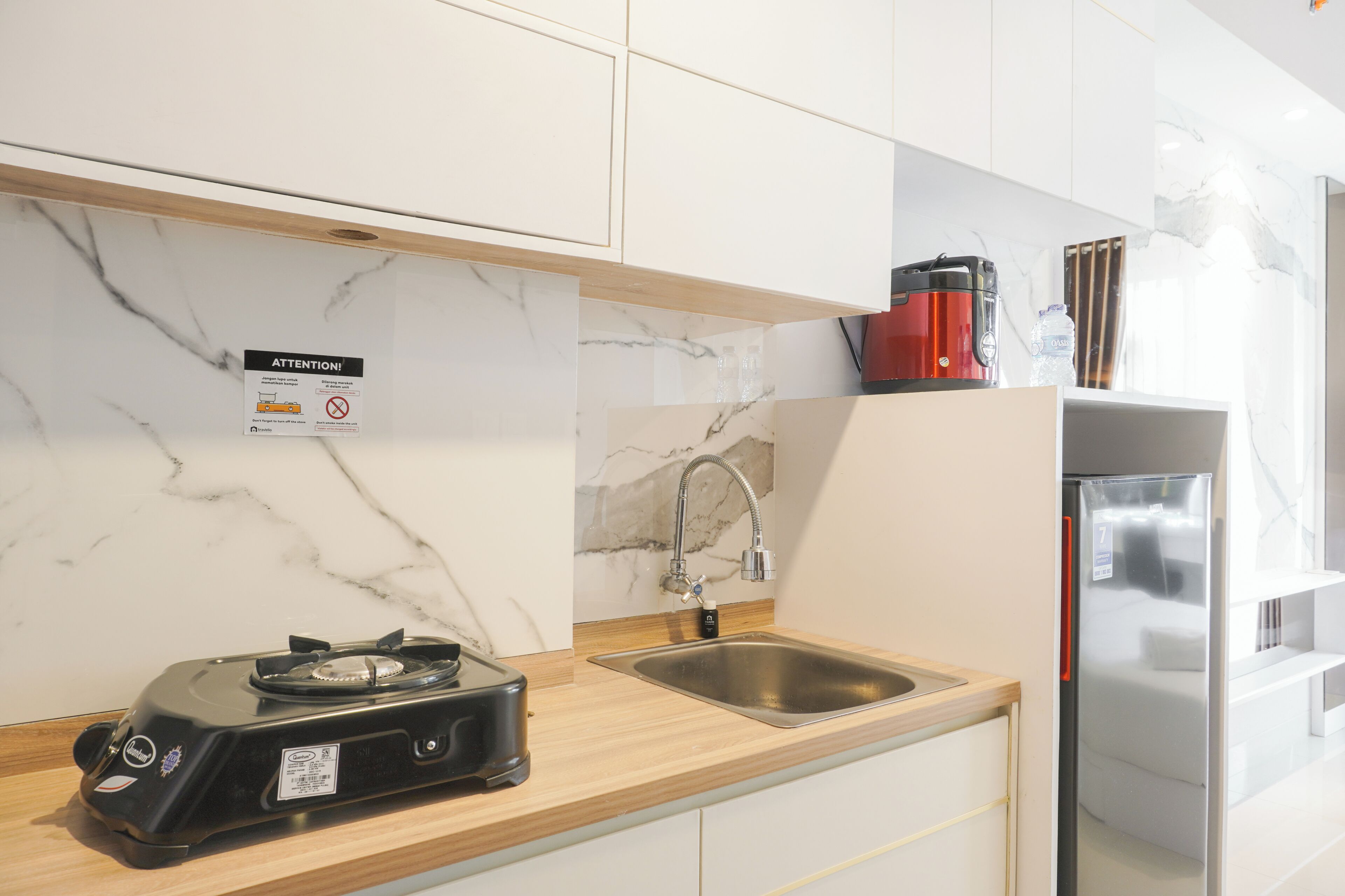 A modern kitchen with a gas stove, stainless steel sink, and a red coffee maker.