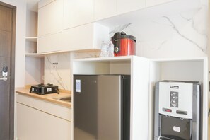 A kitchen with a refrigerator, a water dispenser, and a coffee maker on the countertop. - Nice And Comfy Studio At Citra Living Apartment (Jakarta)