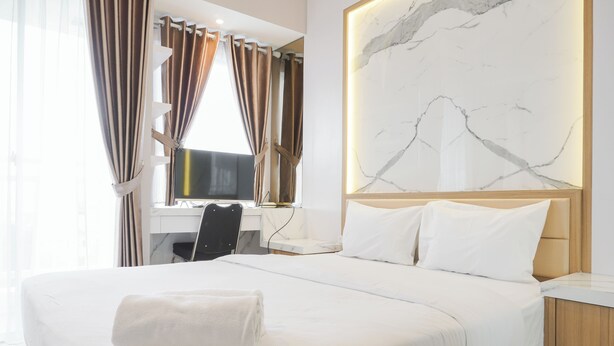 Habitación de hotel con cama, escritorio, silla y una gran obra de arte de mármol en la pared.