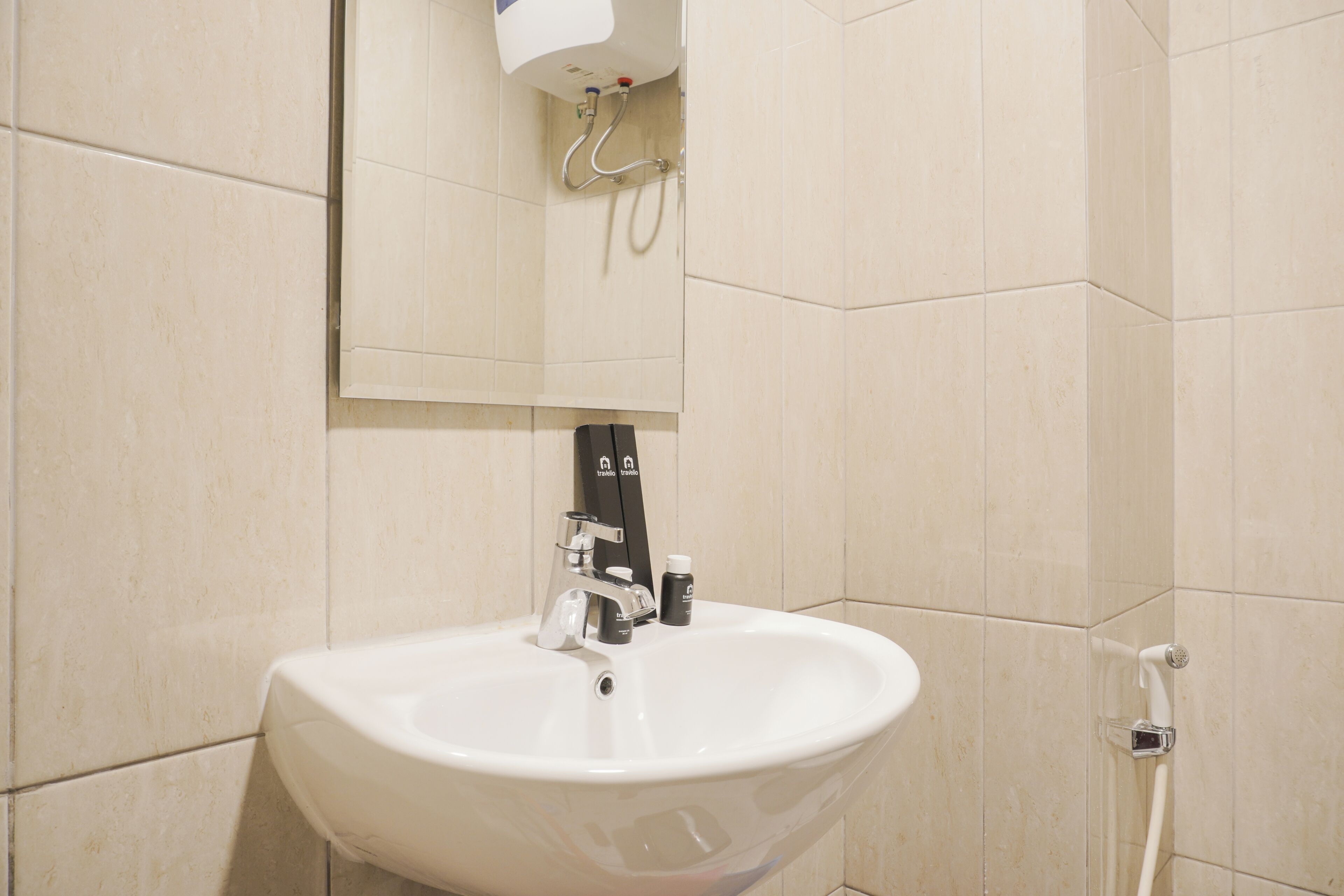 Ein Badezimmer mit einem weißen Waschbecken, einem Spiegel darüber und einer Duschbrause an der Wand.