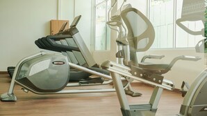Un gimnasio con equipo de ejercicio, incluyendo una cinta de correr y una máquina elíptica, en un espacio con amplios ventanales.
