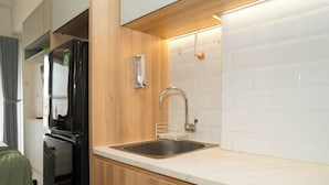 A modern kitchen with a stainless steel sink, wooden cabinets, and a built-in dishwasher. - Comfortable Space And Neat Studio At Apartment Citra Living (Jakarta)