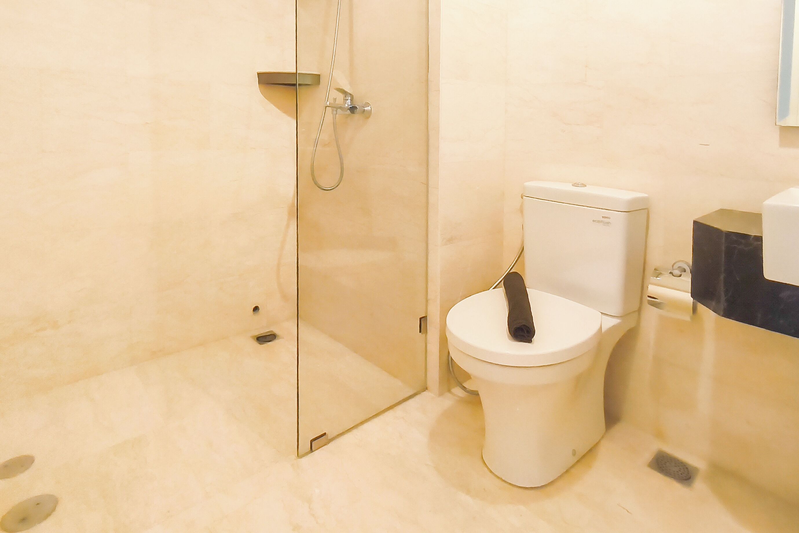 A bathroom with a toilet, shower, and a marble floor.
