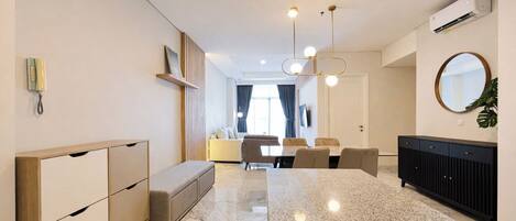 A modern hotel room with a marble floor, a dining area with a table and chairs, a sofa, a black console, and a large mirror.