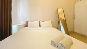 A hotel room with a bed, two pillows, a bedside table, a mirror, and a wardrobe. - Lovely 1Br (No Living Room) At Apartment Cordova Edupartment Semarang (Semarang)