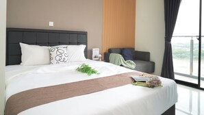 A modern hotel room with a large bed, a sofa, a view of the outdoors, and a window with curtains. - Comfortable And Decent Studio At Apartment Daan Mogot City (Jakarta)