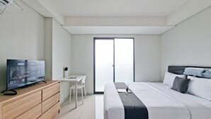 Una habitación de hotel moderna con una cama, un escritorio, un televisor y una puerta corredera al exterior.