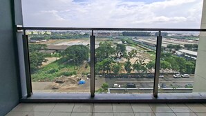 Vista desde un balcón con cielo despejado, un estacionamiento y edificios a lo lejos.
