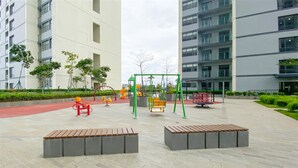 Un parque infantil con columpios, un tobogán y una estructura roja para escalar.
