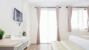 Ein modernes Zimmer mit Schreibtisch, gepolstertem Sitzbänkchen und Wand-TV.