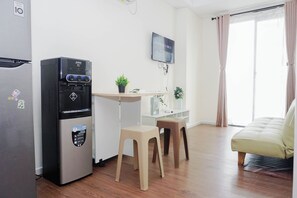 Um espaço compacto com cozinha compacta, televisão de tela plana na parede, sofá e janela com cortinas.