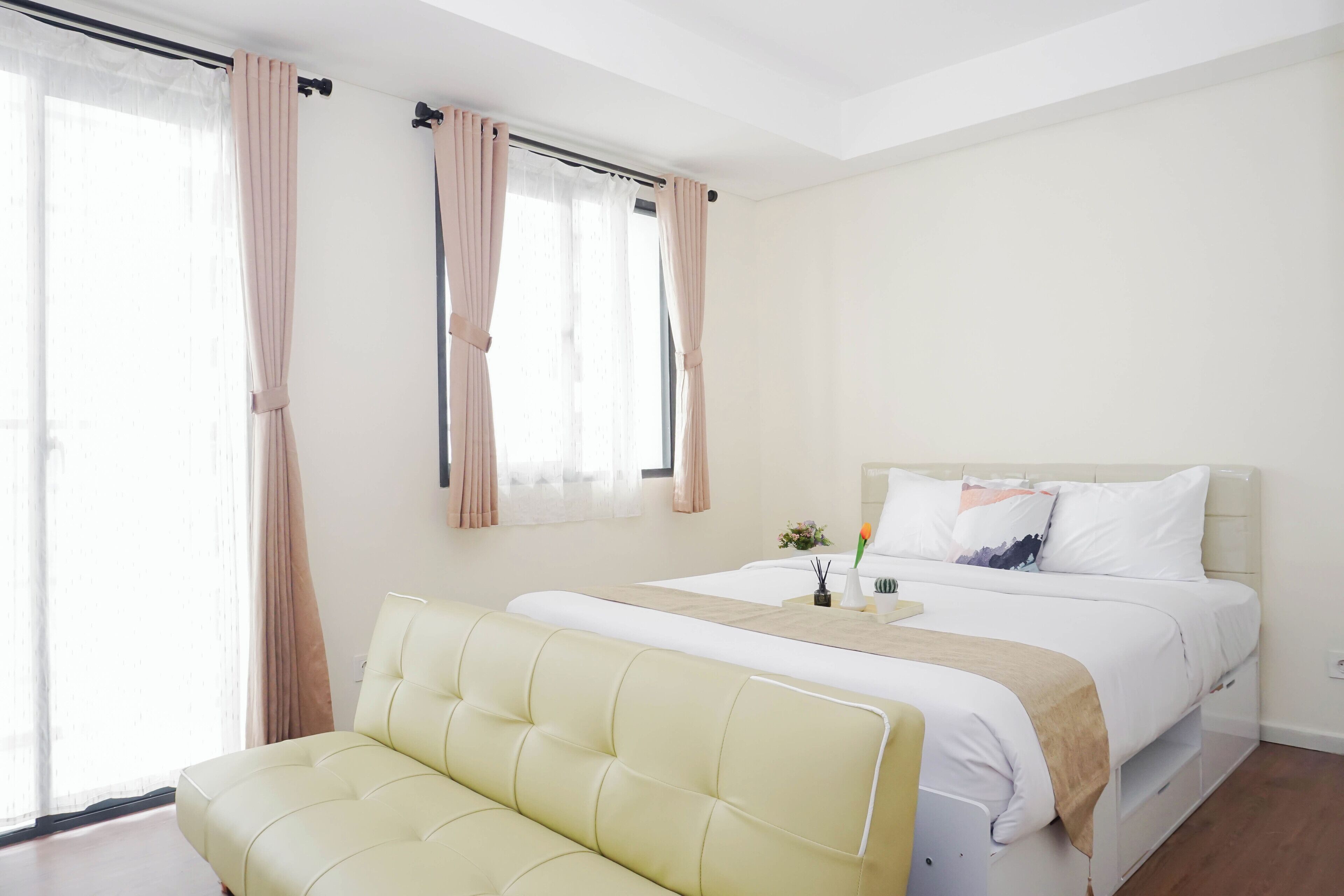 Une chambre à coucher avec un lit, un canapé et une fenêtre avec des rideaux.