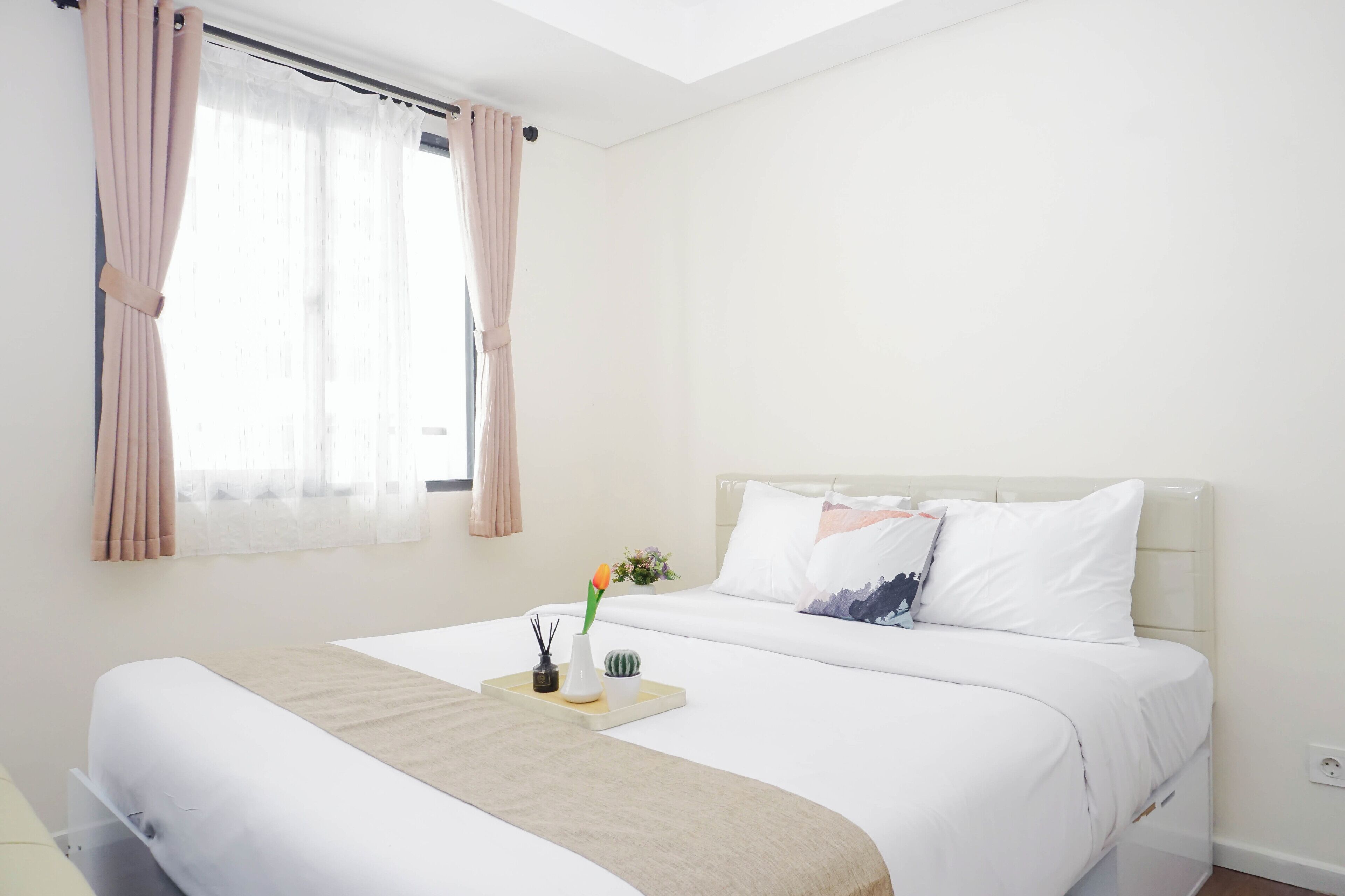 Un dormitorio con cama, cortinas, una mesita de noche y una ventana.