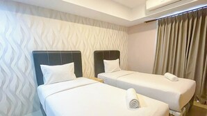 A hotel room with two beds, a patterned wall, an air conditioning unit, and a curtain. - Homely And Pleasant Studio At Apartment De Prima (Medan)