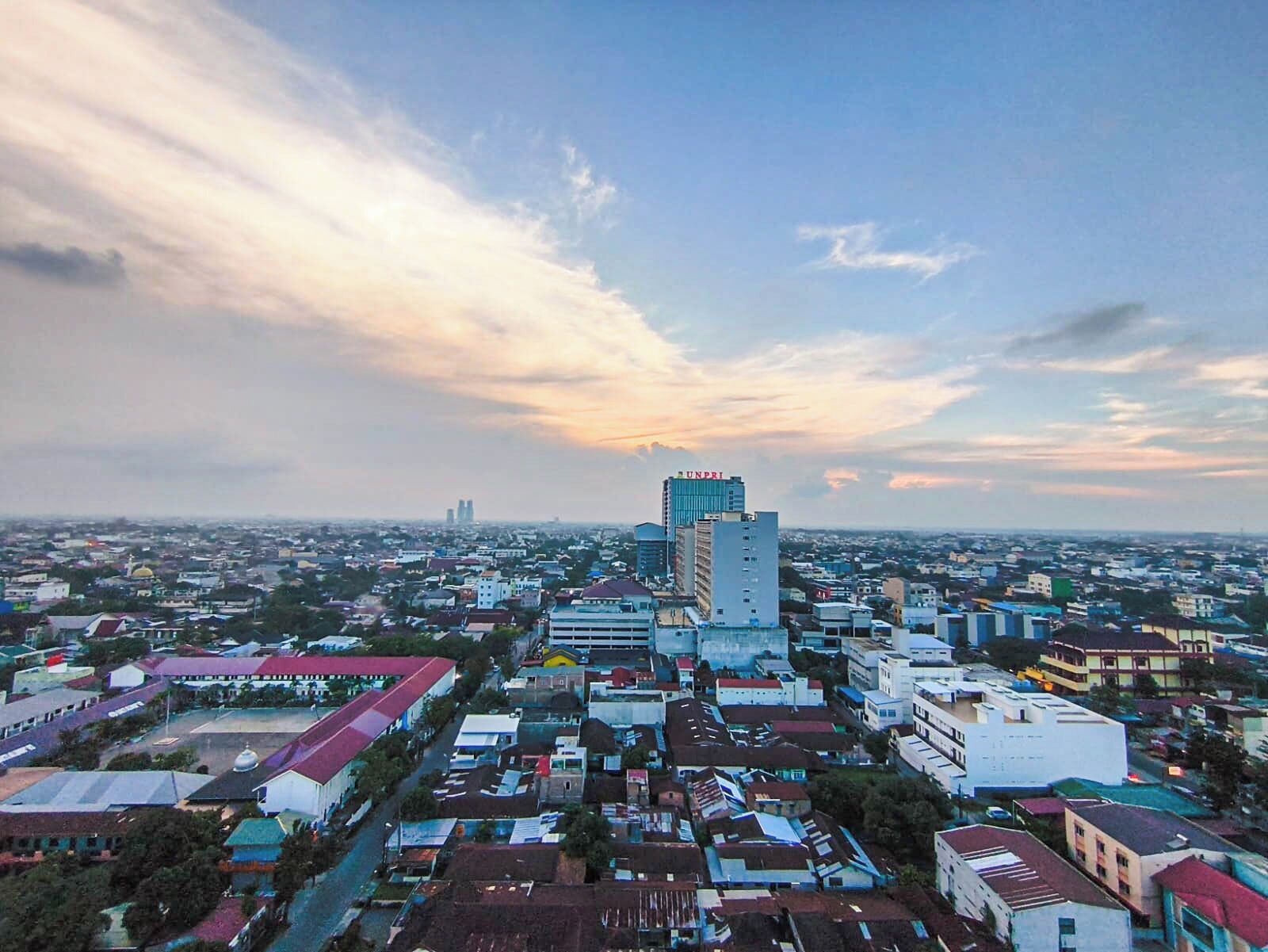 A cityscape with a prominent UNPRI building, various residential and commercial buildings, and a wide street view.