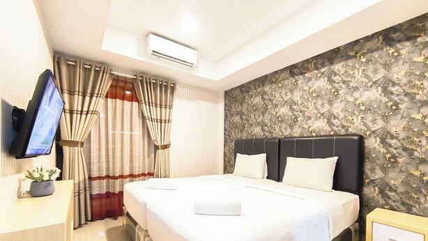 Een hotelkamer met een bed, een televisie, gordijnen, een airconditioner en een wand met een structuur.