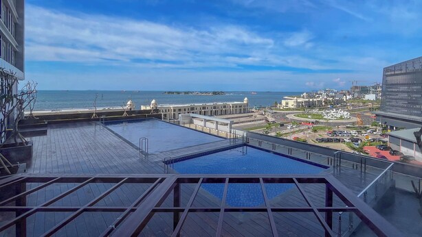 Una piscina en la azotea con vista al mar y al paisaje urbano.