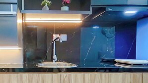Una cocina moderna con salpicadero de mármol, un lavamanos de acero inoxidable y encimera de madera.