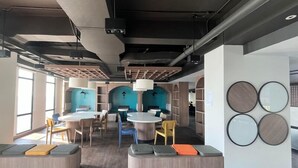 Un espacio de oficina moderno con mesas redondas, zonas de estar y una pared con espejos circulares.