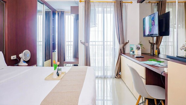 Una camera d'albergo con un letto, una scrivania, una TV e ampie finestre.