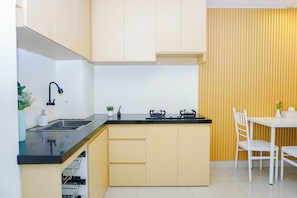 Cocina compacta con lavamanos, cocina y un pequeño comedor con sillas.