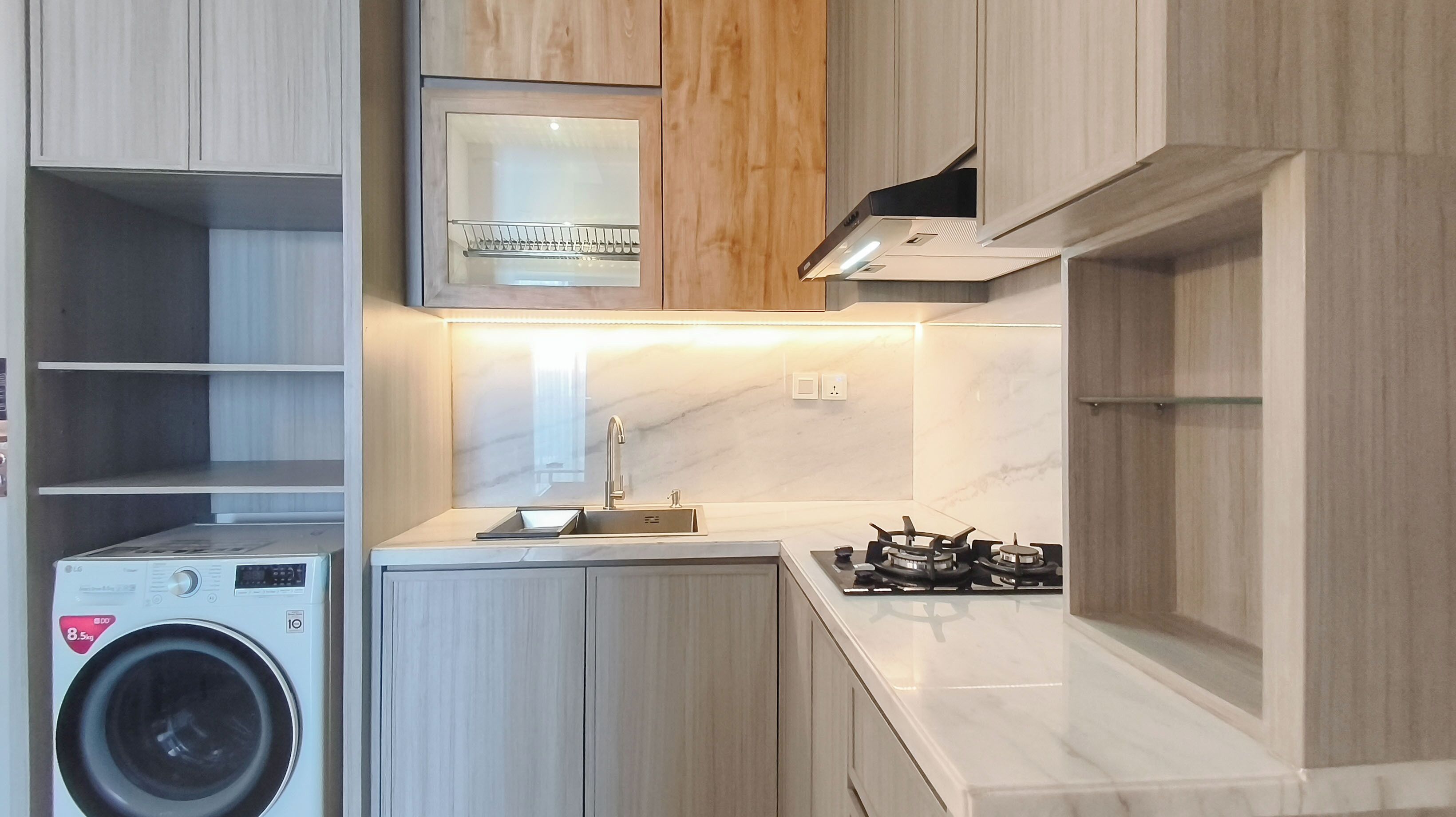 A compact kitchen with a built-in washing machine, a gas stove, and wooden cabinetry.
