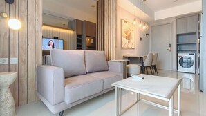 Ein modernes Wohnzimmer mit einer Couch, einem Couchtisch, einem Fernseher und einer Waschmaschine.