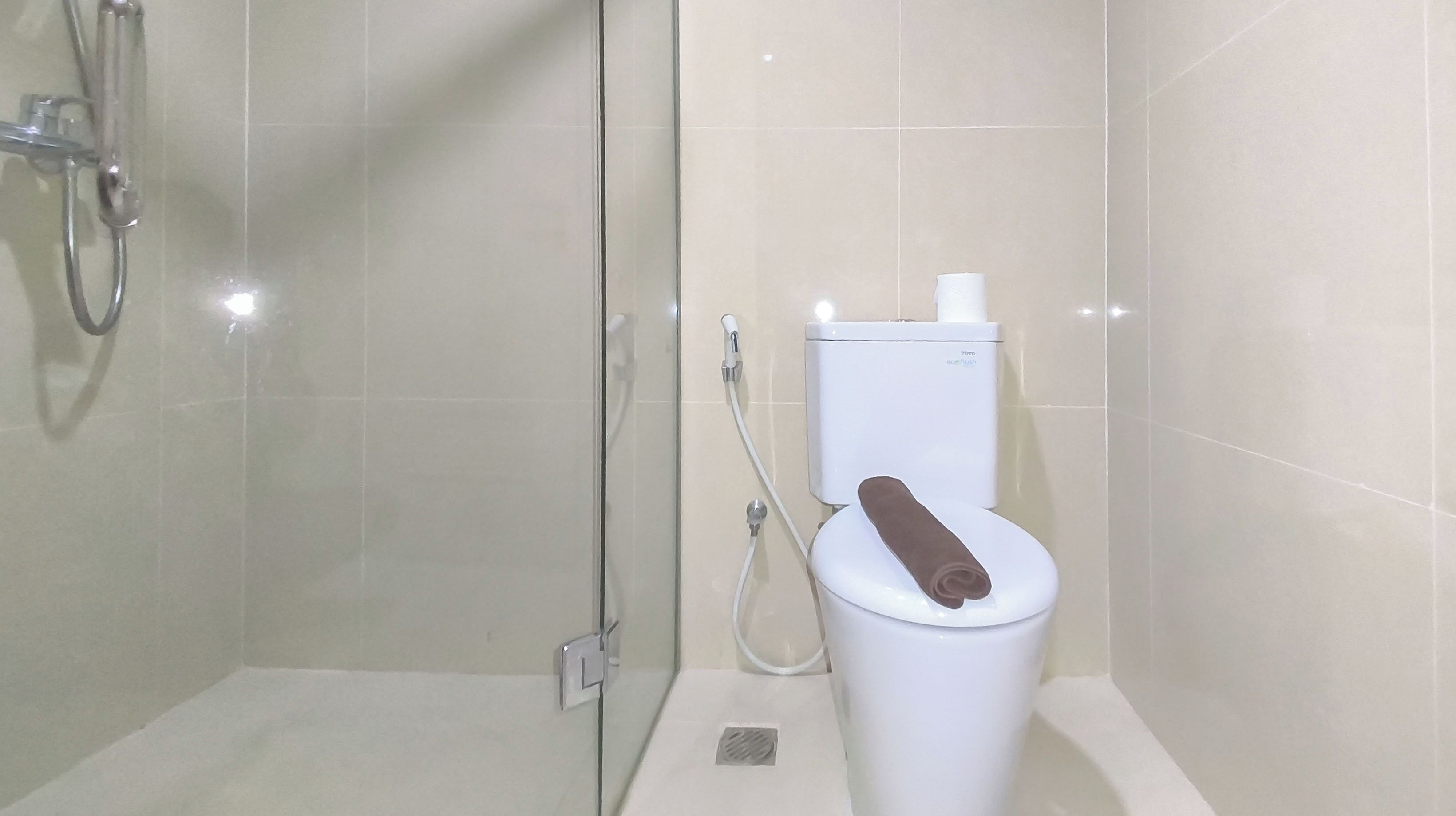 A modern bathroom with a glass-enclosed shower, a toilet with a bidet attachment, and a visible water heater.