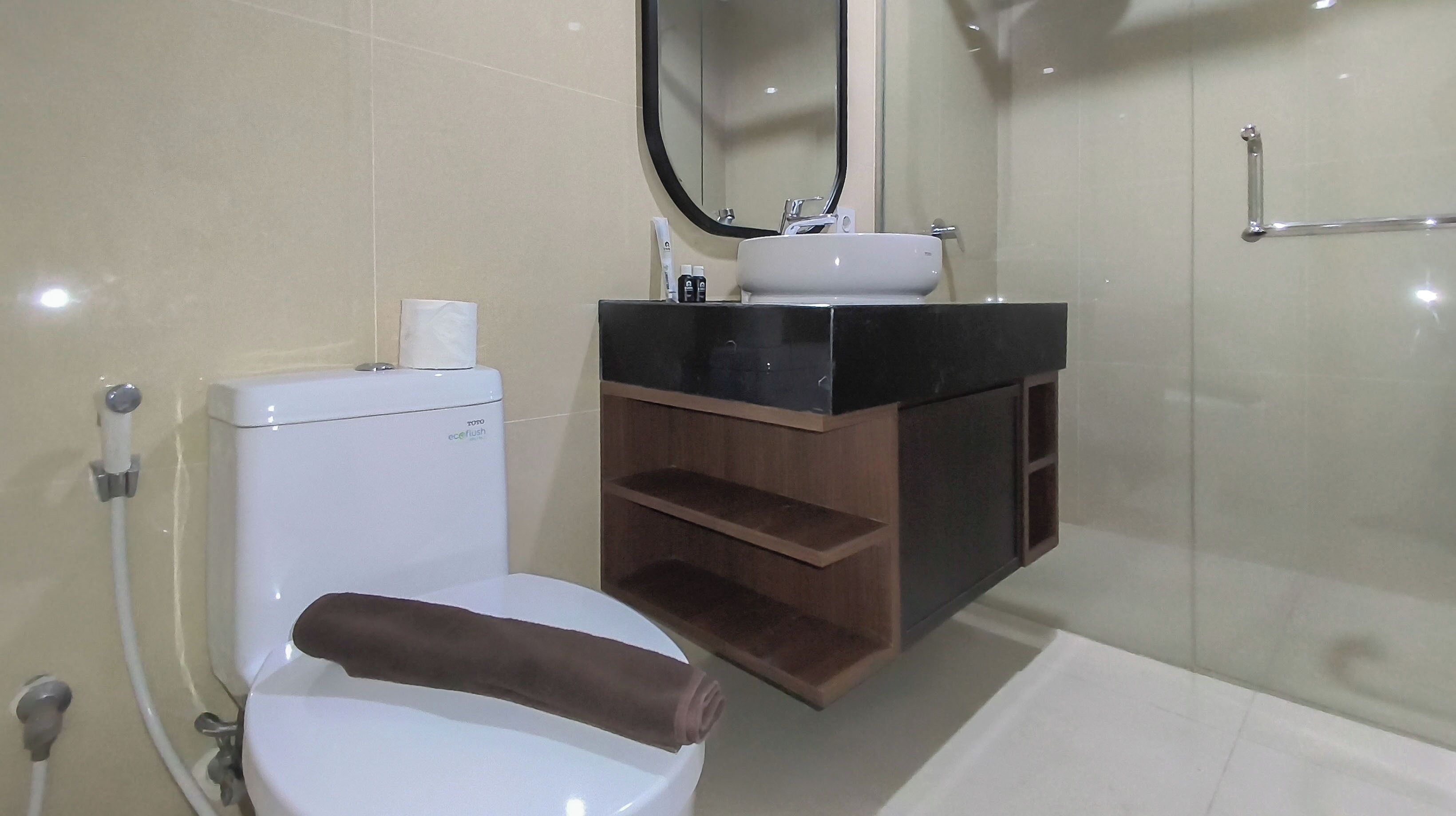 A bathroom with a toilet, a sink, a mirror, and a shower area.