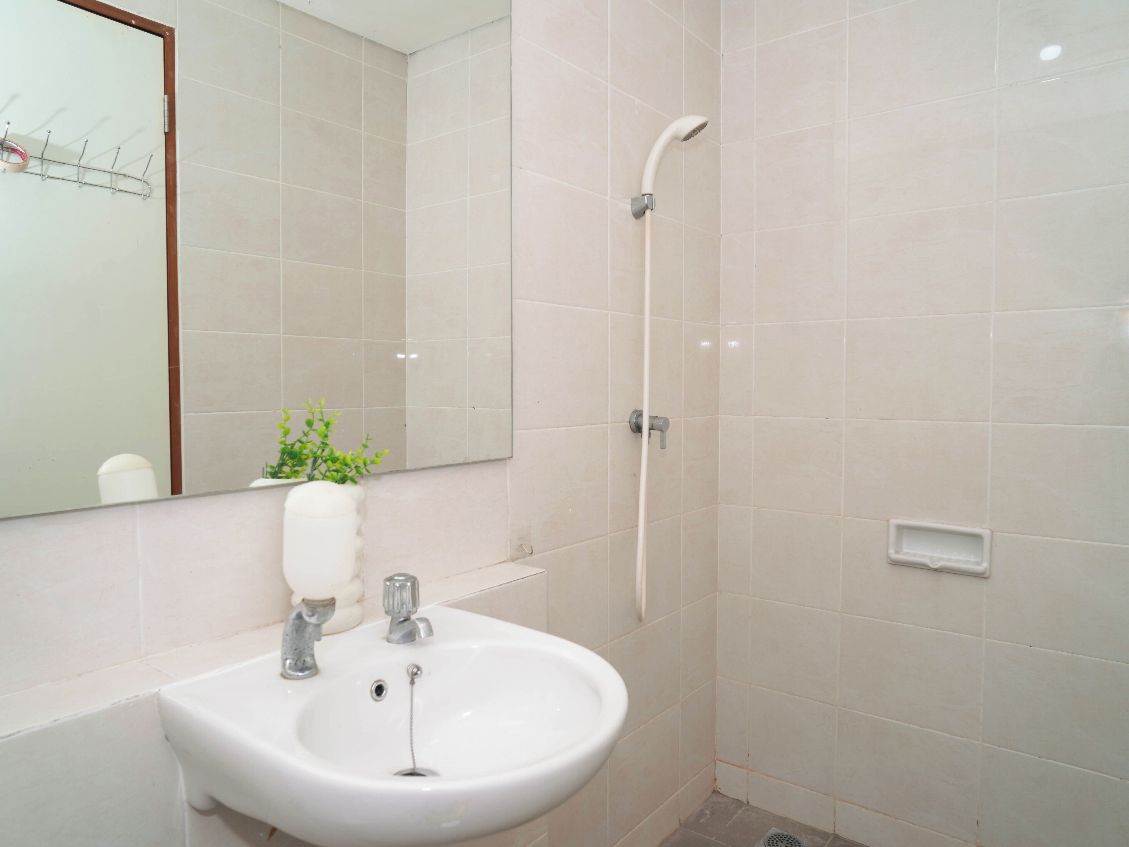 A bathroom with a sink, mirror, shower, and tiled walls.