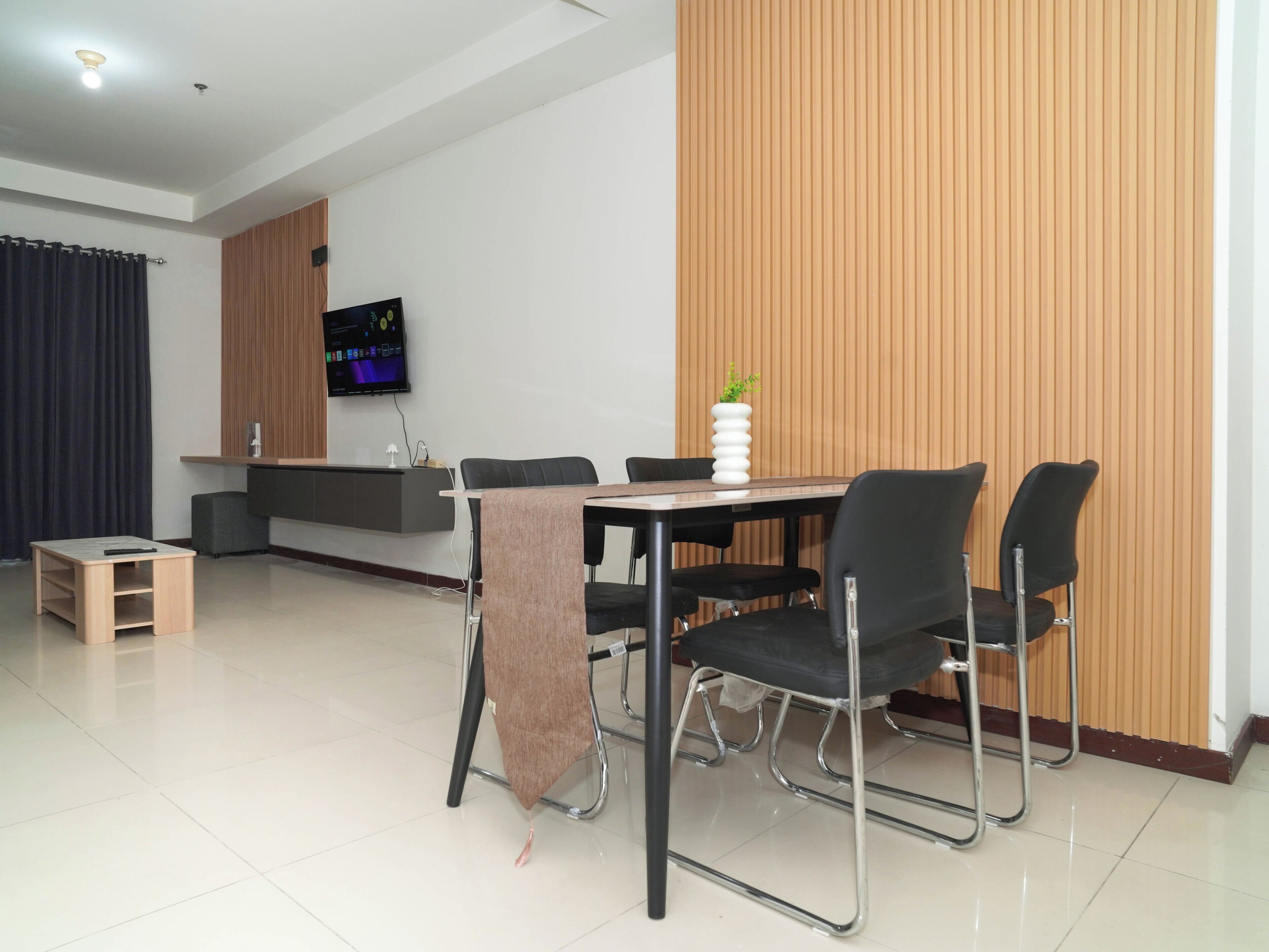 A modern dining area with a table, chairs, a TV, and a wooden accent wall.