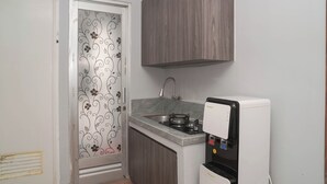 Una cocina compacta con dispensador de agua incorporado, estufa y lavamanos.