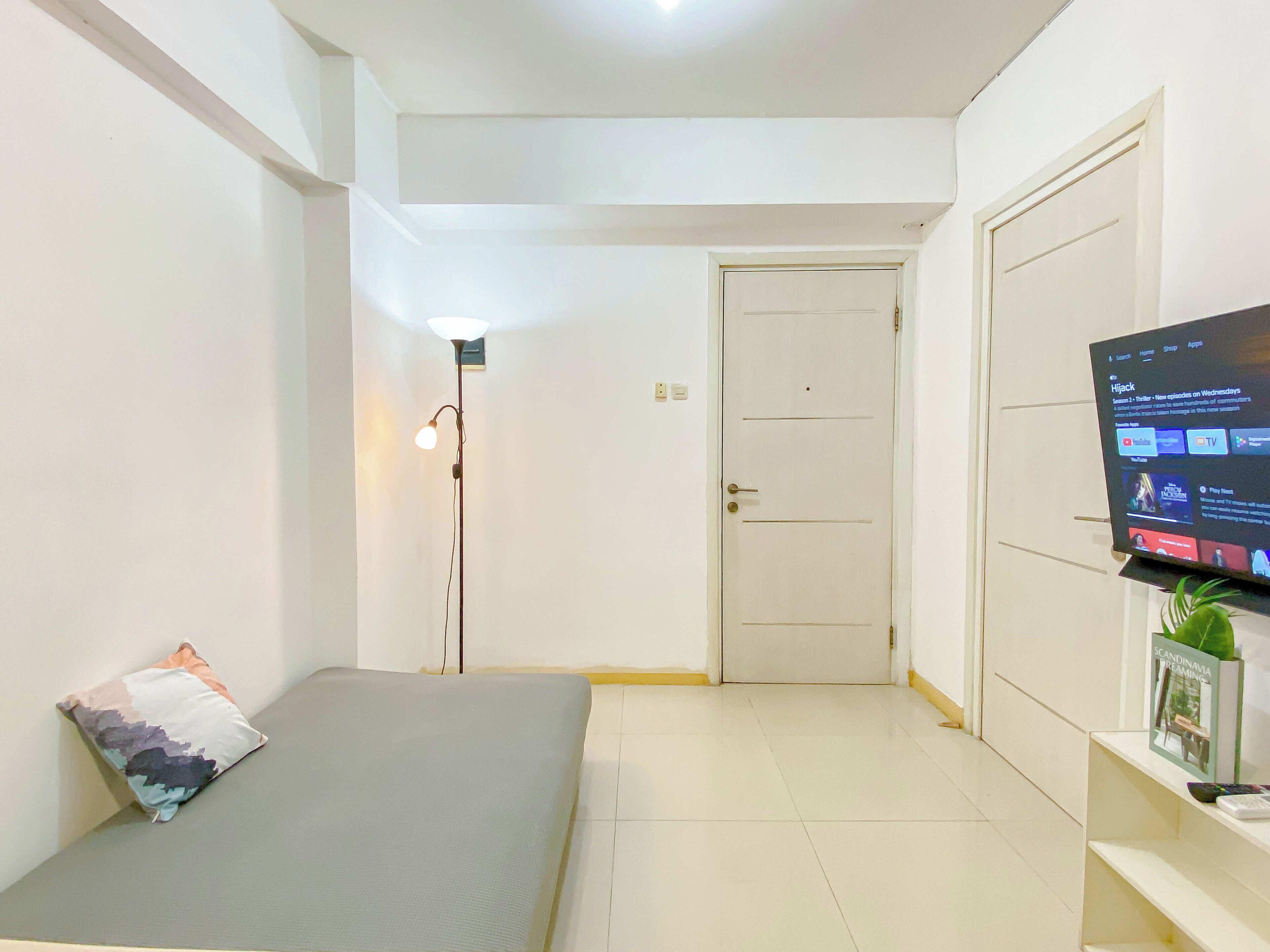 Una camera da letto con un letto, una TV, un armadio e una lampada da terra.