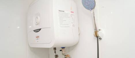 A white water heater with a control panel, a shower head, and a hose.