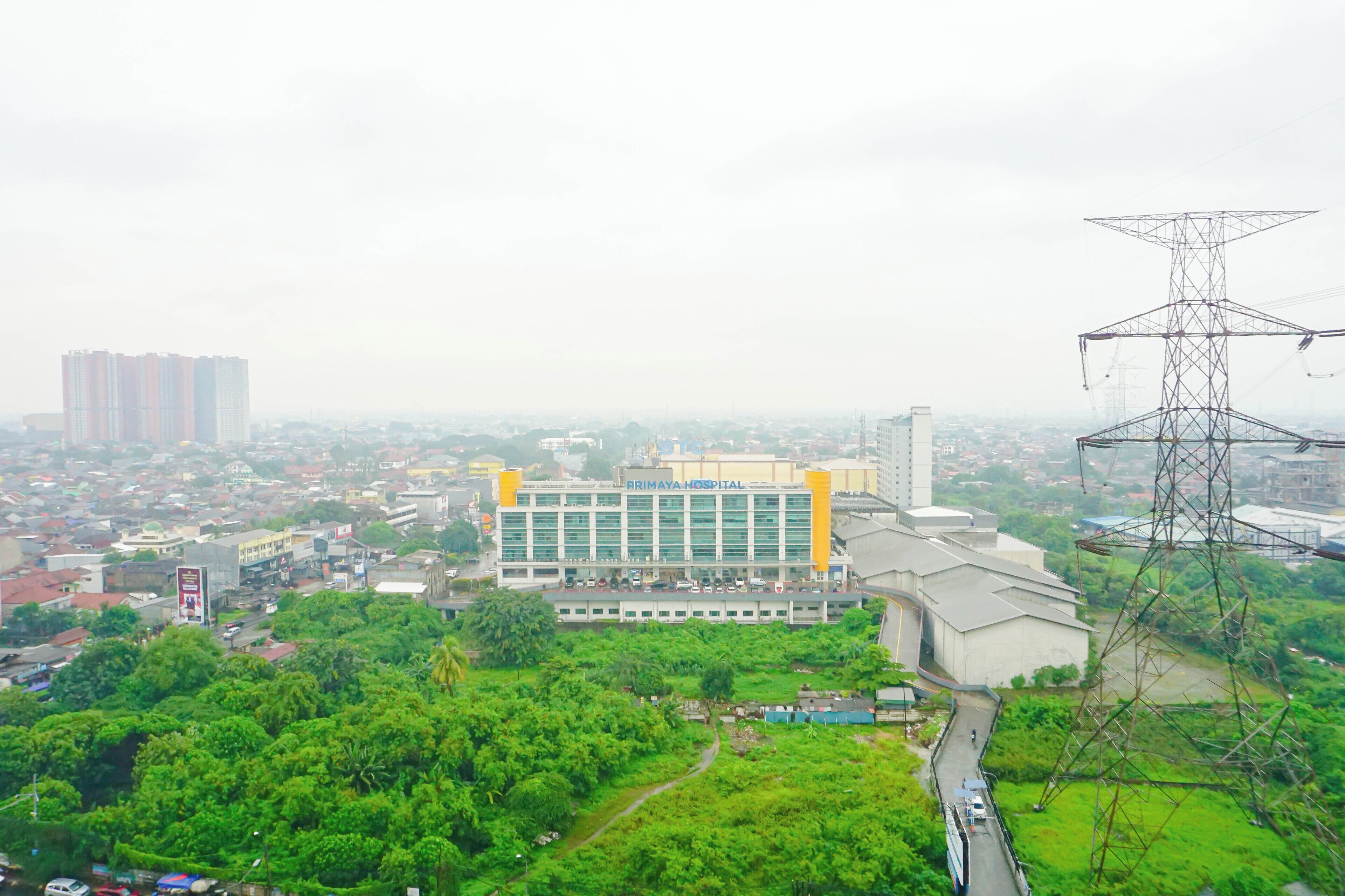A hospital building with a prominent sign, surrounded by greenery and urban infrastructure.