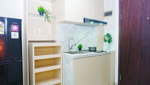 A compact kitchen with a built-in refrigerator, a sink, and a microwave. - Relaxing Stay Studio At Apartment Lrt City Bekasi (Bekasi)