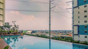 A swimming pool with a view of a bridge and buildings in the background. - Urban Look Studio Apartment At Lrt City Bekasi (Bekasi)