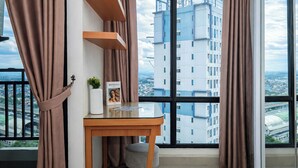 A modern room with a large window, a wooden desk, a chair, and a potted plant. - Urban Look Studio Apartment At Lrt City Bekasi (Bekasi)