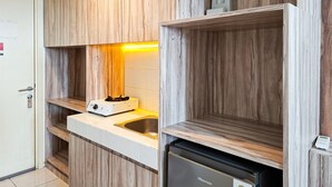 A compact kitchen with wooden cabinetry, a built-in sink, and a Hisense refrigerator. - Great Deal Studio Apartment At M-Town Residence (Gading Serpong)