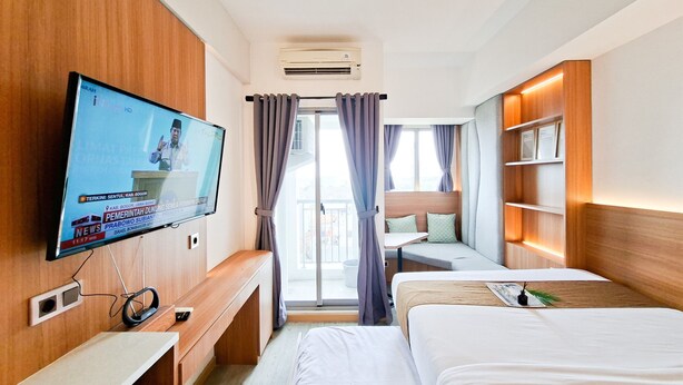 Ein Hotelzimmer mit Fernseher, Schreibtisch, zwei Betten und einem Balkon, an einer Holzwand.