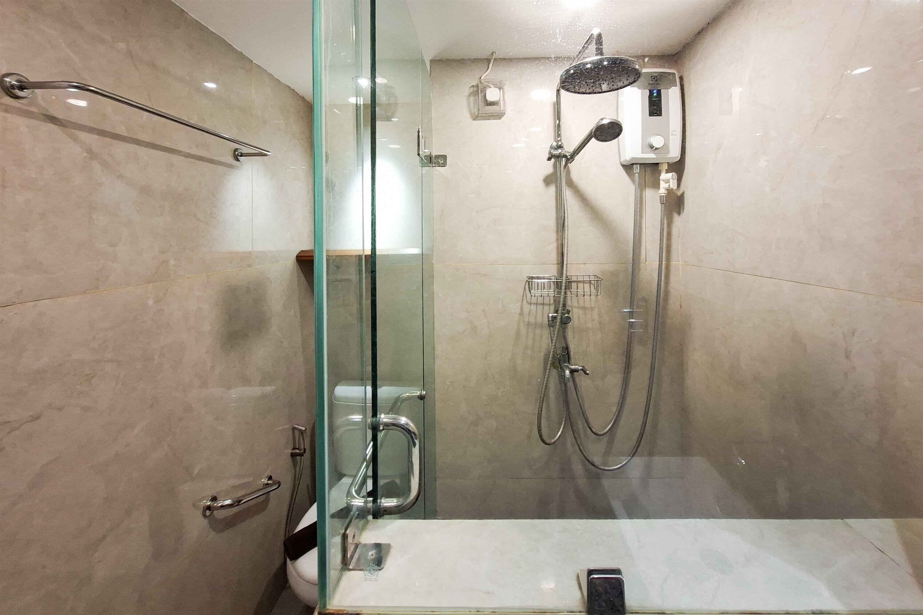 Ein modernes Badezimmer mit Duschkabine aus Glas, Handbrause und einer zusätzlichen Handbrausenhalterung sowie einer Glastür.