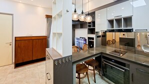 A modern kitchen with a central island, built-in appliances, and pendant lighting. - Functional 2Br With Extra Room At M-Town Residence (Gading Serpong)