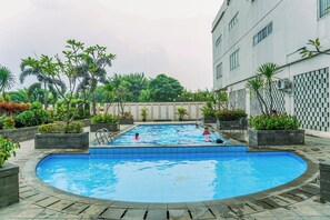 Piscina cercada por vasos e um edifício.