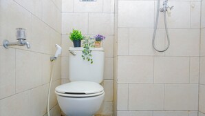 Ein Badezimmer mit Toilette, Dusche und zwei Blumentöpfen auf dem Toilettentank.