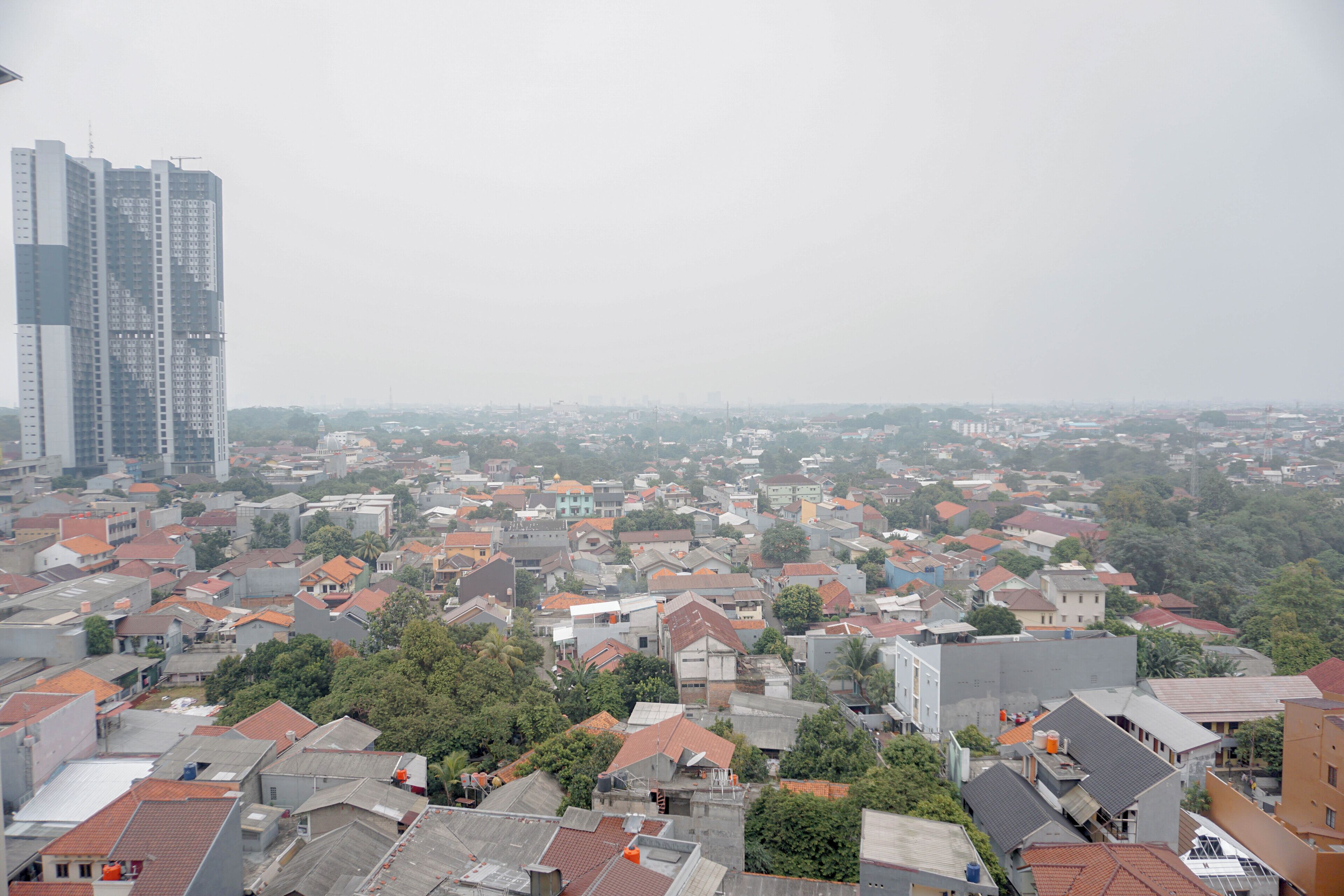 A cityscape with residential buildings, a large high-rise building, and a dense urban environment.